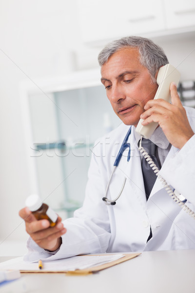 Doctor holding a phone and drug box in a medical office Stock photo © wavebreak_media