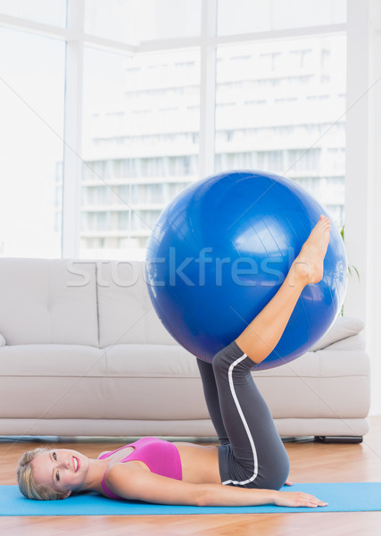 Smiling blonde holding exercise ball between legs Stock photo © wavebreak_media