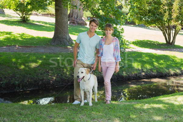 Happy couple standing with their labrador in the park smiling at Stock photo © wavebreak_media