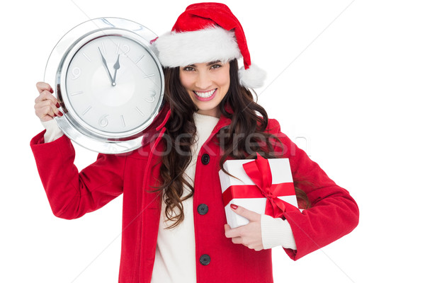 Festive brunette holding a clock and gift Stock photo © wavebreak_media
