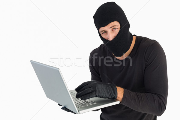 Burglar standing holding laptop while looking at camera Stock photo © wavebreak_media