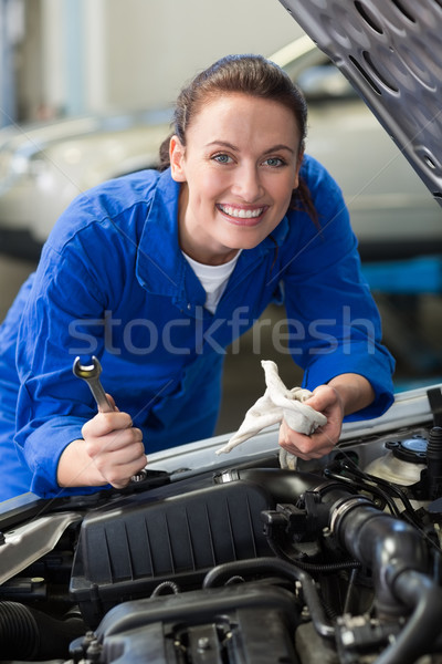 Mechanic smiling at the camera fixing engine Stock photo © wavebreak_media