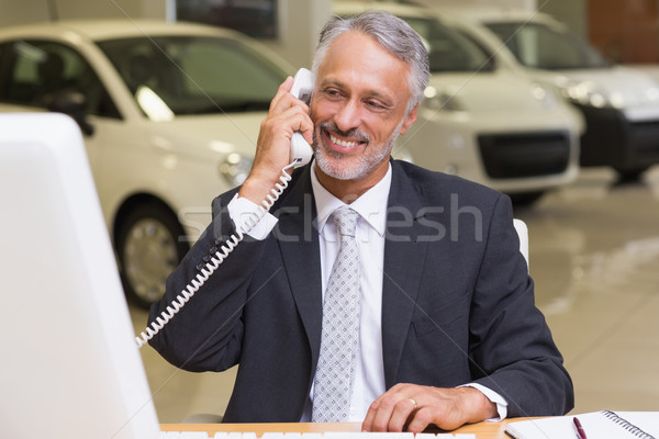 Smiling businessman using phone in front of computer Stock photo © wavebreak_media