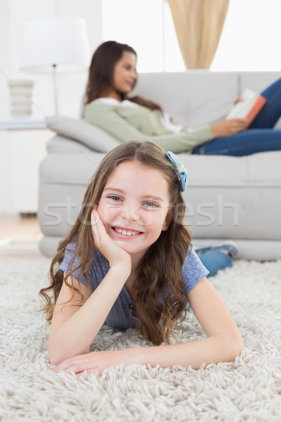 Happy girl lying on rug while mother relaxing at home Stock photo © wavebreak_media