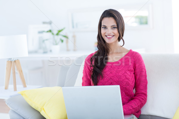 Sonriendo hermosa morena usando la computadora portátil sofá salón Foto stock © wavebreak_media