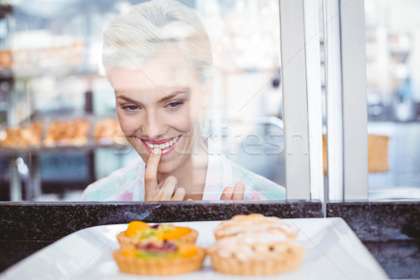 Hesitating pretty woman looking at fruit pie Stock photo © wavebreak_media