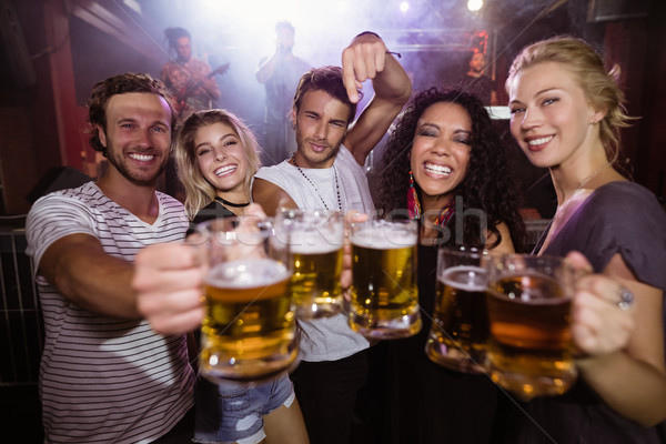 Portrait of happy friends holding beer mugs at nightclub Stock photo © wavebreak_media