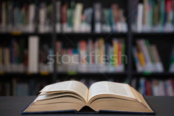 Close up of open book on table against shelf Stock photo © wavebreak_media