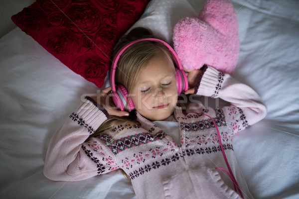 Girl listening to music on headphones while lying on bed Stock photo © wavebreak_media