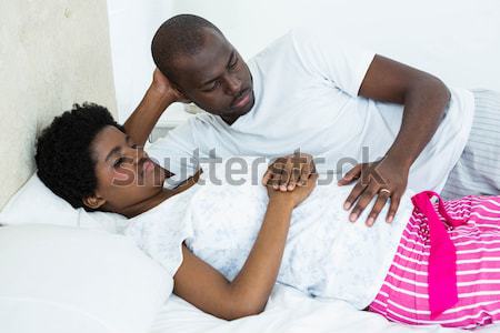 Man placing baby shoes on womans belly in bedroom Stock photo © wavebreak_media