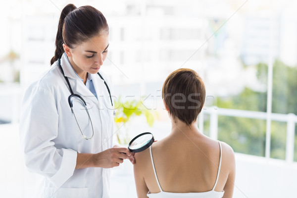 Doctor examining patient with magnifying glass Stock photo © wavebreak_media