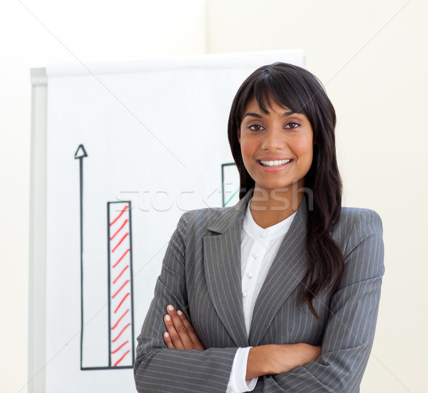 Stock photo: Afro-american businesswoman with folded arms in front of a board