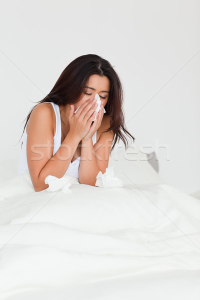 brunette woman having a cold sitting in bed in bedroom Stock photo © wavebreak_media
