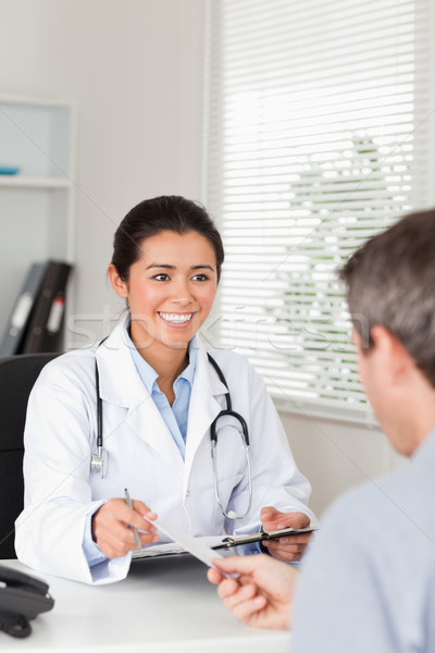 Stock photo: Patient giving his pretty female doctor a piece of paper in her office