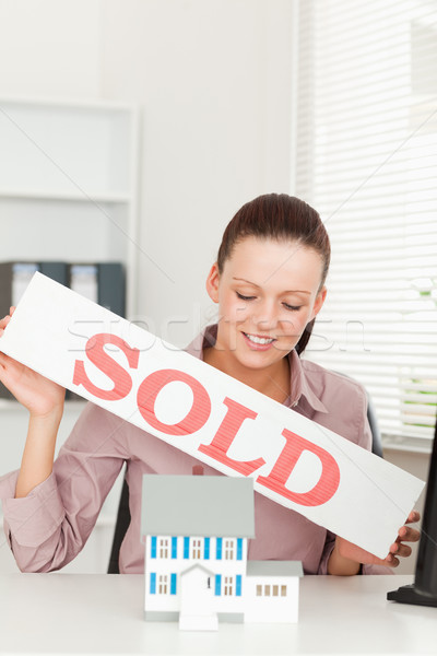 A businesswoman is holding a sold sign above a miniature house Stock photo © wavebreak_media