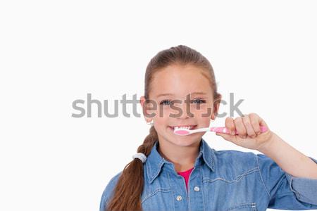 Healthy girl brushing her teeth against a white background Stock photo © wavebreak_media