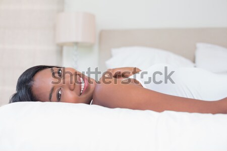 A woman lying on a bed, head turned to her side. Eyes open and smiling. Stock photo © wavebreak_media
