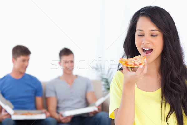 A smiling woman about to eat a slice of pizza as her friends sit behind her  Stock photo © wavebreak_media