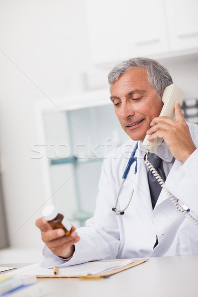 Doctor holding a drug box and a phone in a medical office Stock photo © wavebreak_media
