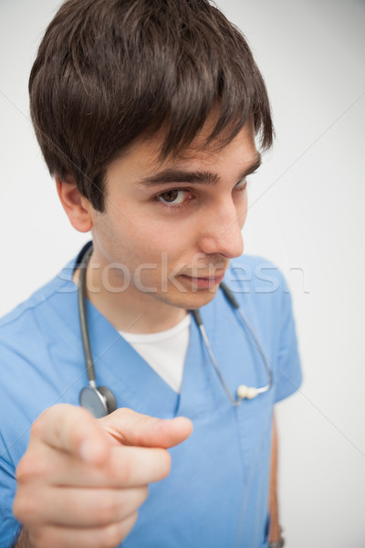 Stock photo: Nurse is pointing at the camera wearing scrubs