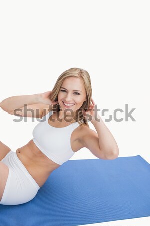 Stock photo: Portrait of happy young woman doing sit-ups on exercise mat