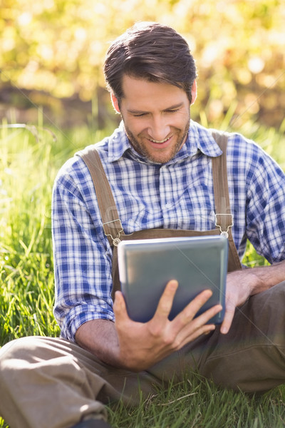 улыбаясь фермер цифровой таблетка сидят трава Сток-фото © wavebreak_media