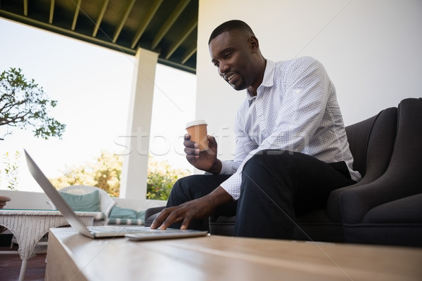 Foto d'archivio: Imprenditore · tazza · di · caffè · utilizzando · il · computer · portatile · usa · e · getta · cafe