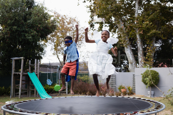 Playful siblings in costumes enjoying on trampoline Stock photo © wavebreak_media