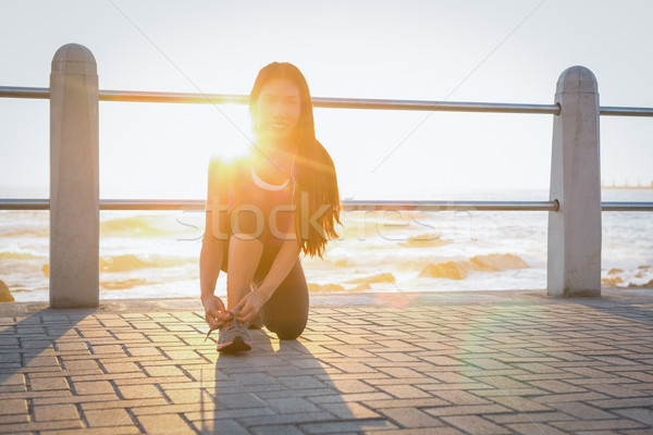 Smiling fit woman tying her shoelace at promenade Stock photo © wavebreak_media