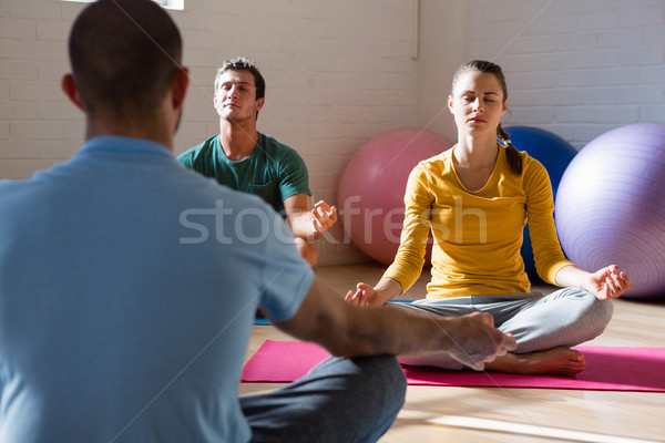 Instructor guiding students in meditation at health club Stock photo © wavebreak_media