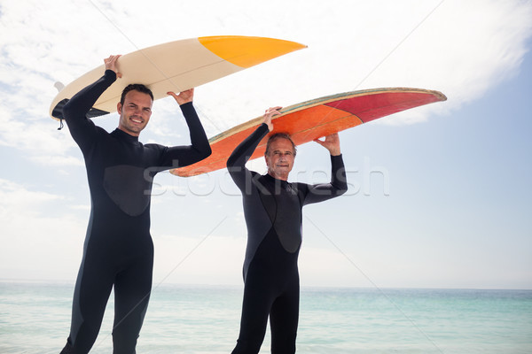 Portrait of happy father and son carrying a surfboard over their Stock photo © wavebreak_media