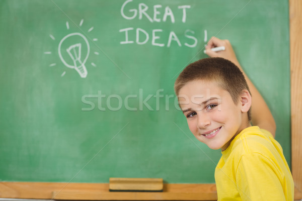 Smiling pupil writing on chalkboard in a classroom Stock photo © wavebreak_media