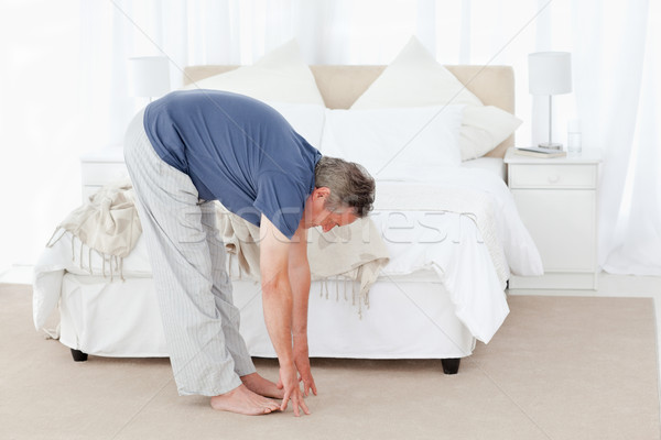 Stock photo: Mature man stretching in his bedroom