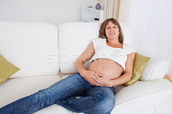 Attractive pregnant woman posing while lying on a sofa in her apartment Stock photo © wavebreak_media