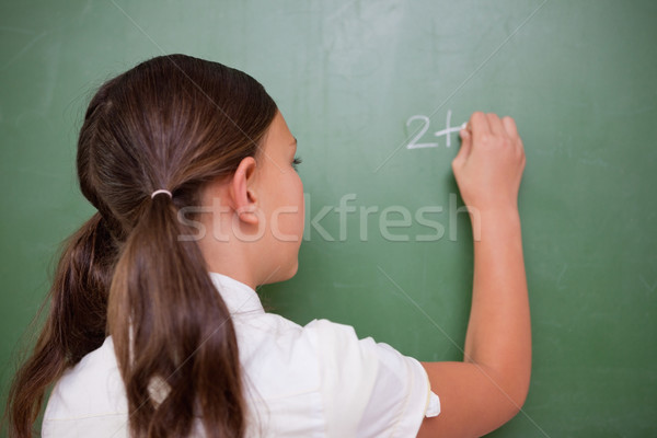 Schoolgirl writing an addition on a blackboard Stock photo © wavebreak_media