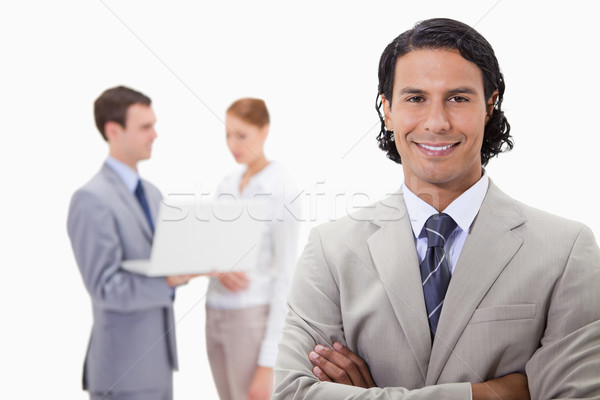 Stock photo: Smiling businessman with colleagues working on laptop behind him against a white background