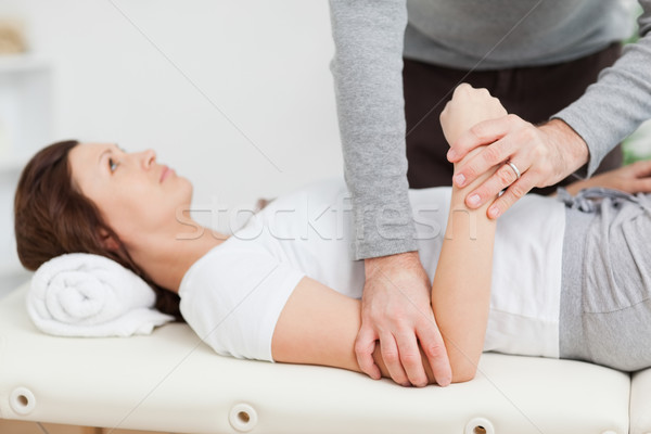Physiotherapist manipulating the arm of a peaceful woman in a room Stock photo © wavebreak_media