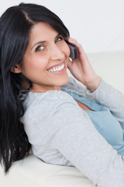 Femeie zambitoare telefon ureche camera de zi telefon Imagine de stoc © wavebreak_media