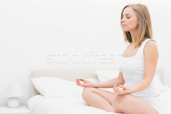 Woman sitting in lotus position with eyes on bed Stock photo © wavebreak_media