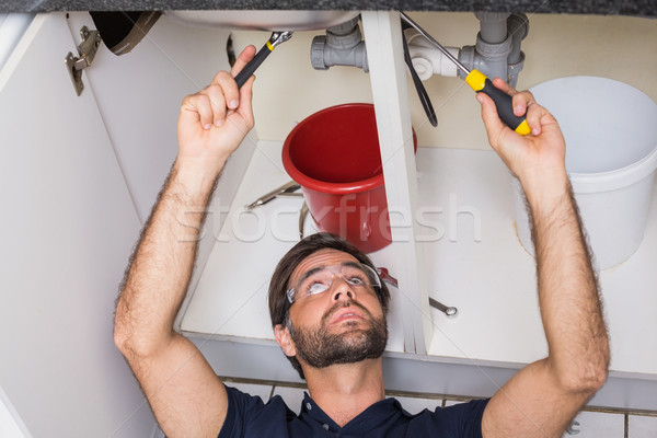 Stock photo: Plumber fixing under the sink