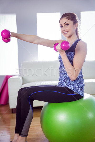 Fit woman lifting dumbbells on exercise ball Stock photo © wavebreak_media