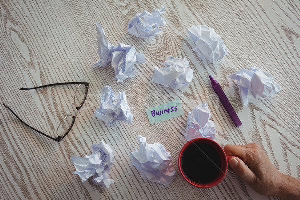 Hand of businesswoman holding coffee cup by crumpled papers on desk in office Stock photo © wavebreak_media