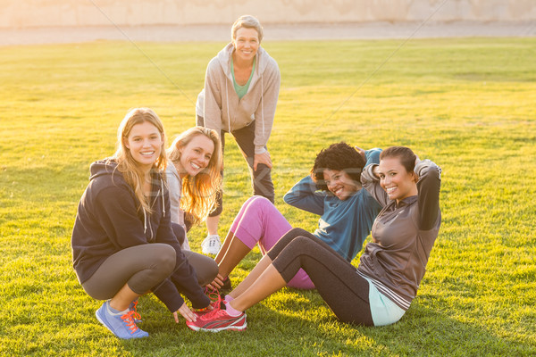 Stock photo: Smiling sporty women doing sit ups during fitness class