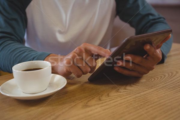 Stock photo: Mid section of man with coffee using tablet in cafe