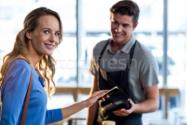 Woman paying bill through smartphone using NFC technology Stock photo © wavebreak_media