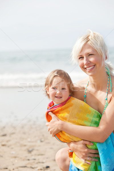 Stock photo: A cheerful girl in a towel and her smiling  mother at the beach