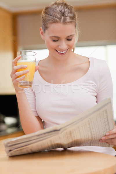 Stock photo: Portrait of a woman reading the news while drinking orange juice in her kitchen