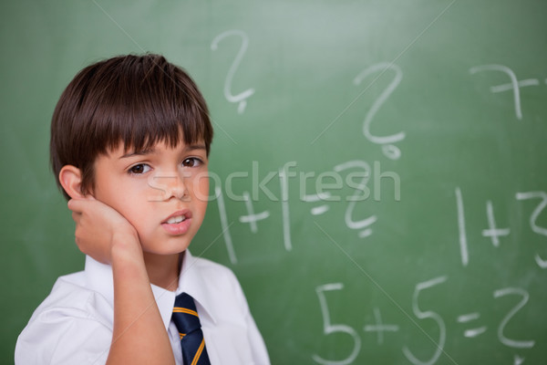 Stock photo: Confused schoolboy thinking while scratching the back of his head in a classroom