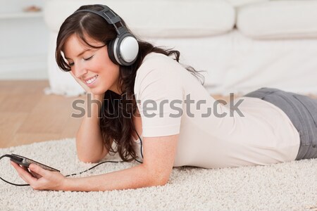 A woman using a tablet and headphones, on the bed, with a focused look upon her face. Stock photo © wavebreak_media