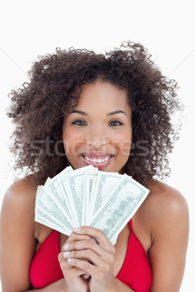 Stock photo: Smiling brunette holding a fan of bank notes against a white background